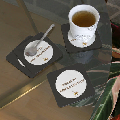 Untersetzer „Cheers to new beginnings“ auf einem Tisch mit Kaffeetasse im Einsatz. Als Geschenkidee für einen neuen Anfang.